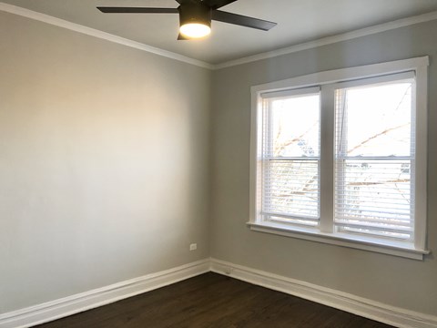 A room with a ceiling fan and a window with blinds.