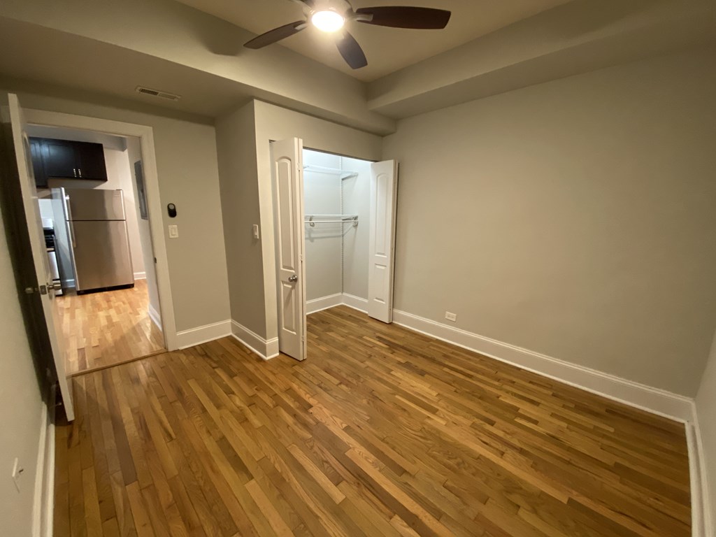 A room with wooden flooring and a ceiling fan.