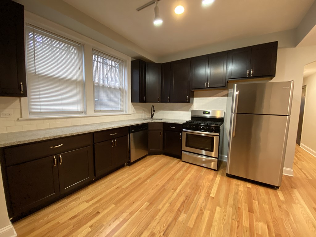 A kitchen with wooden floors and black cabinets.