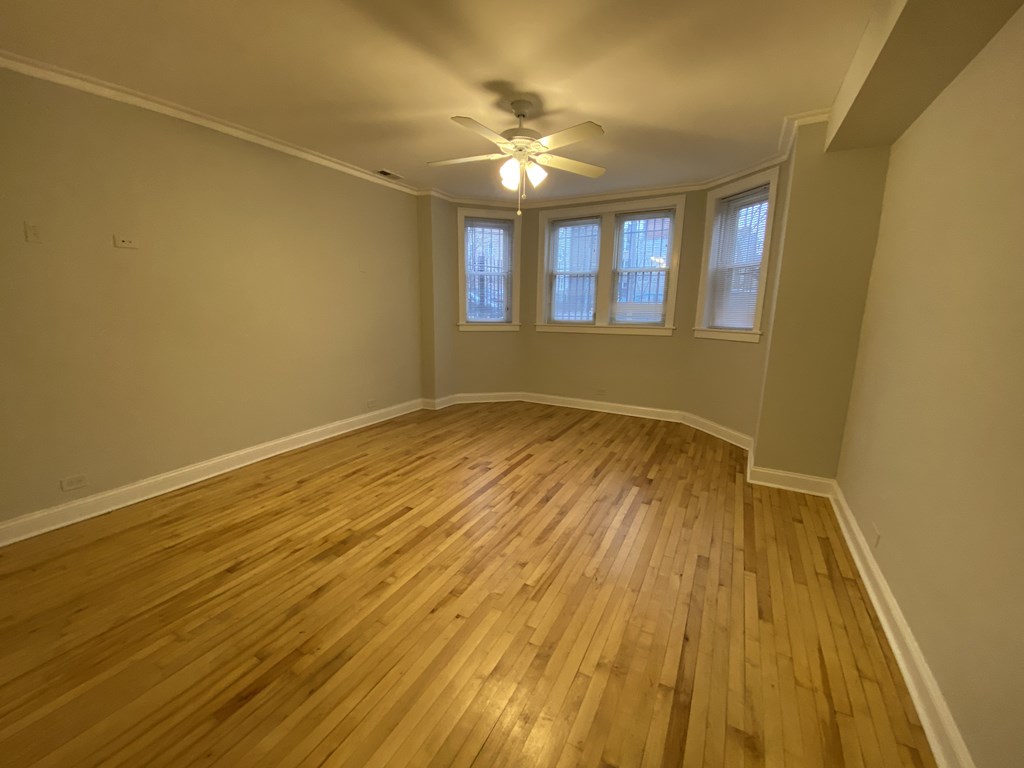 A room with wooden flooring and a ceiling fan.