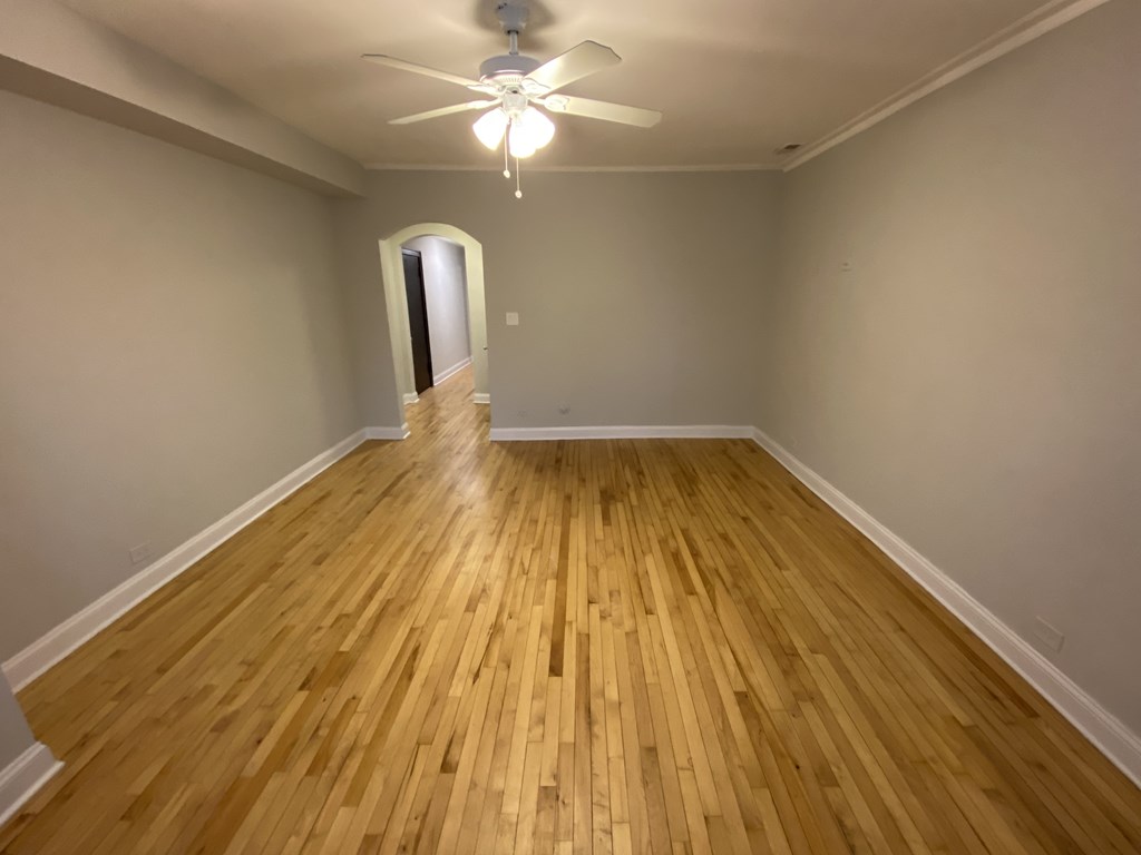A room with wooden flooring and a ceiling fan.