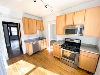 an empty kitchen with wood floors and wooden cabinets