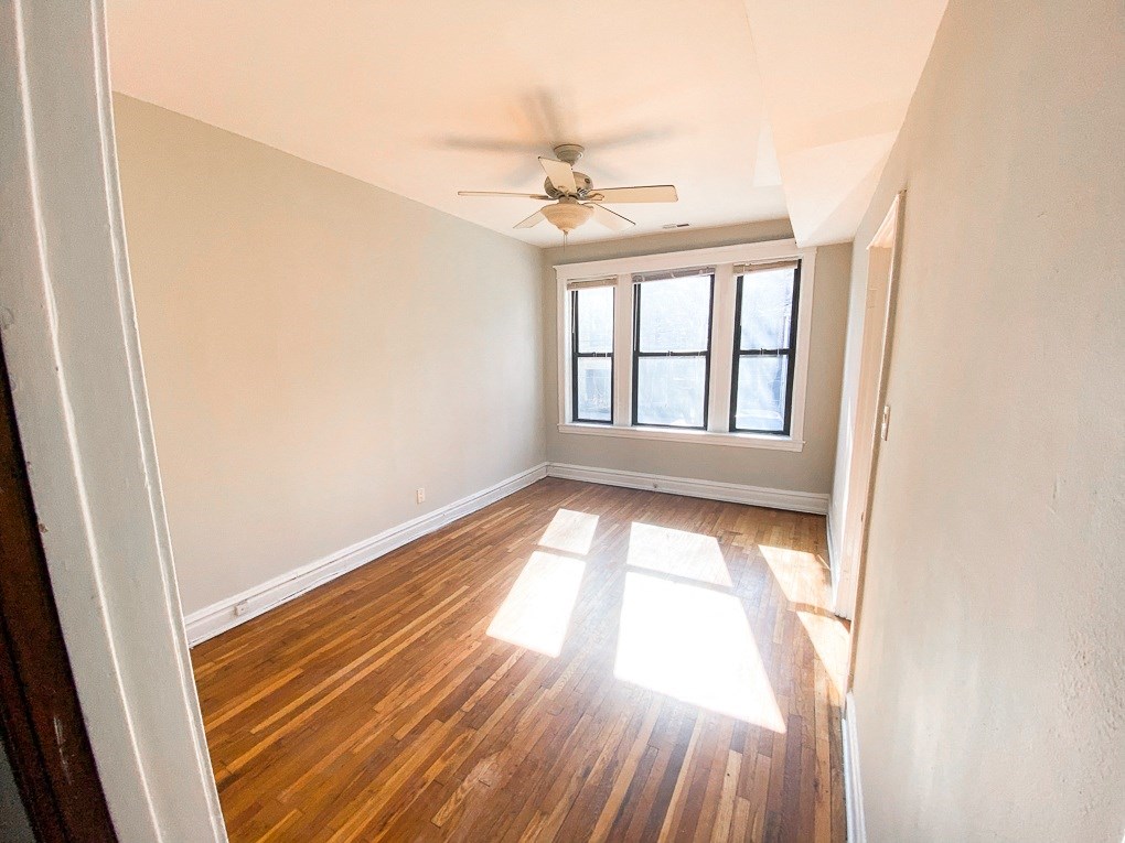 a bedroom with hardwood floors and a ceiling fan