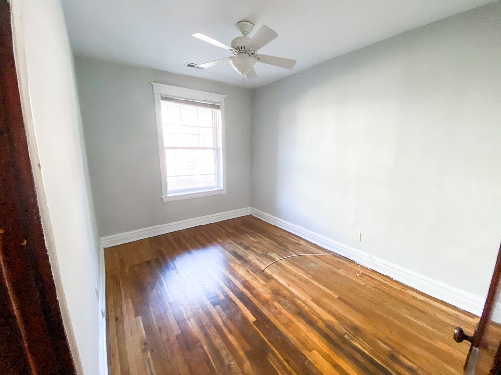 an empty room with hardwood floors and a ceiling fan