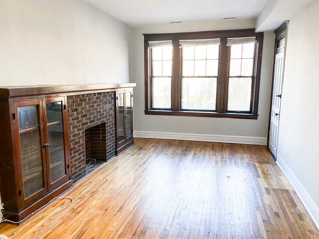 a living room with hardwood floors and a brick fireplace