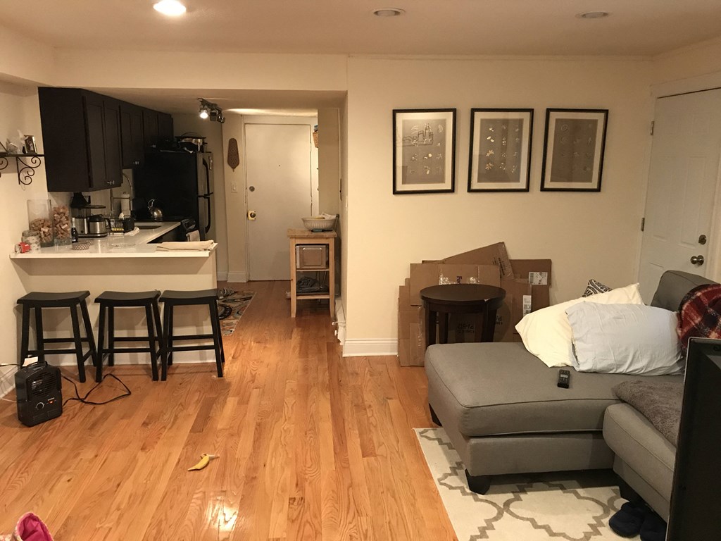 a living room with a couch and a kitchen with boxes on the floor