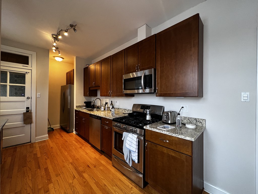 full kitchen with stainless steel appliances and wooden cabinets in an apartment
