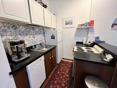 A kitchen with a white fridge and a black counter top.