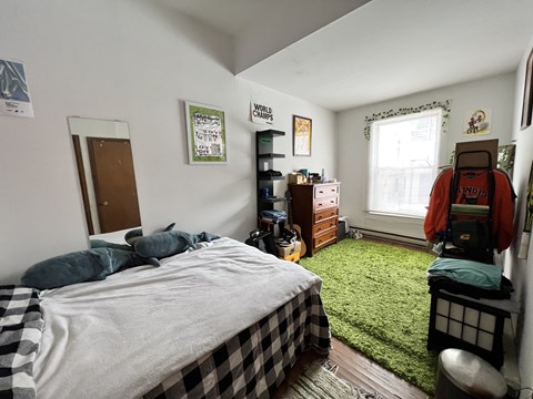 A bedroom with a bed, dresser, and window.