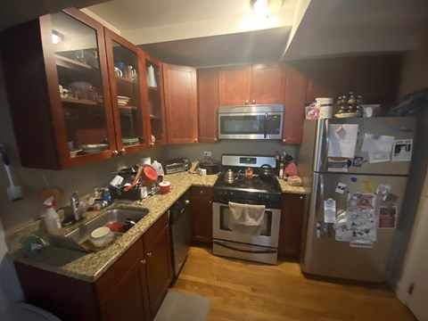 A kitchen with wooden cabinets and a stainless steel refrigerator.