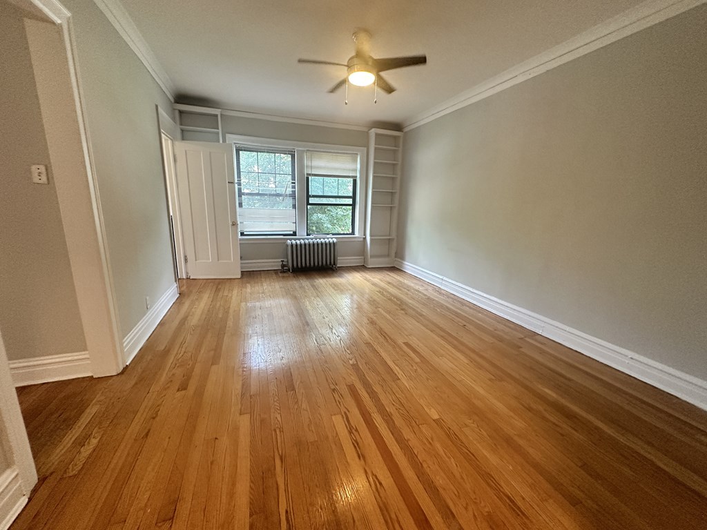 an empty living room with wood floors and a ceiling fan