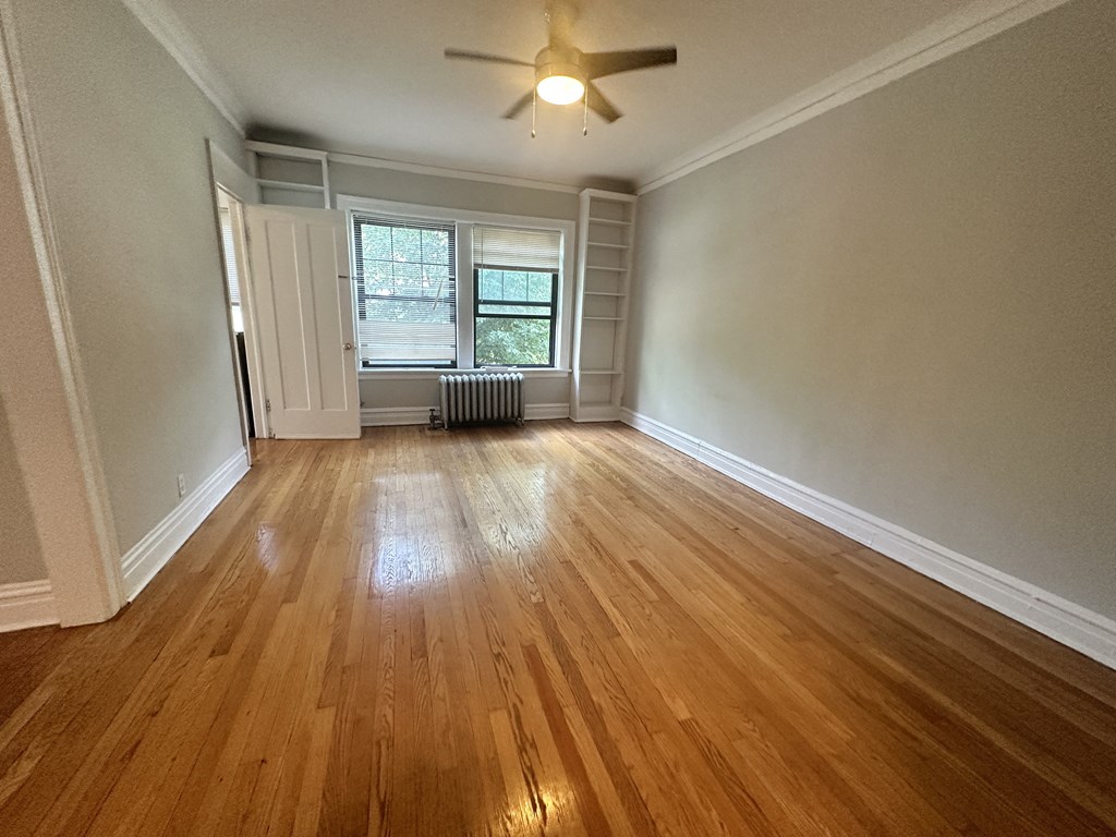 an empty living room with wood floors and a ceiling fan
