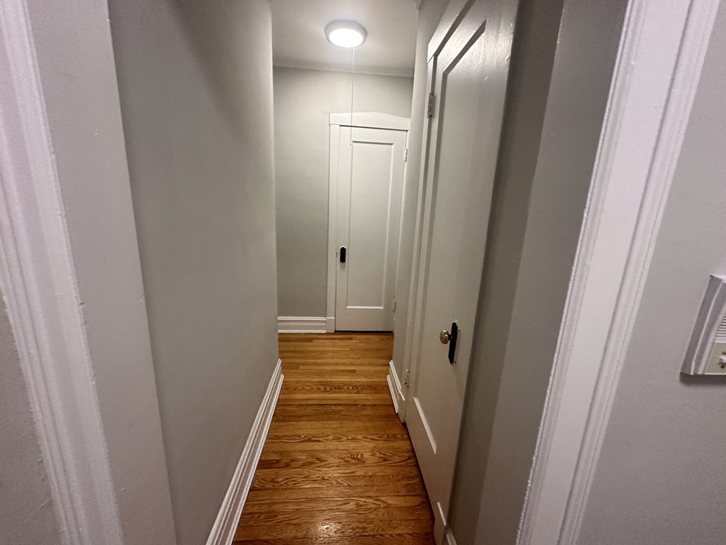 a small hallway with a white door and wood floors