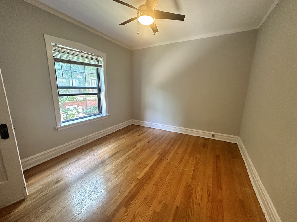 an empty bedroom with hardwood floors and a ceiling fan