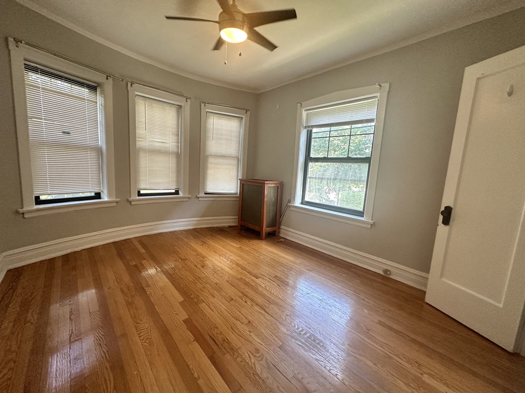 an empty living room with wood floors and a ceiling fan