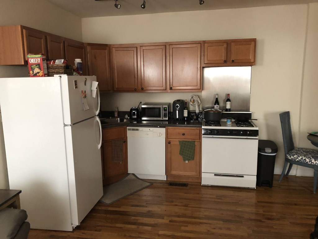 A kitchen with wooden cabinets and a white refrigerator.