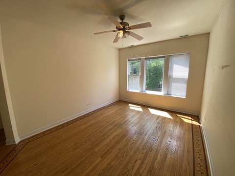 A room with a ceiling fan and wooden flooring.