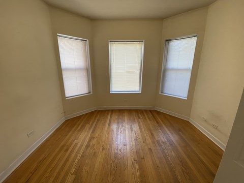 A room with wooden floors and two windows.