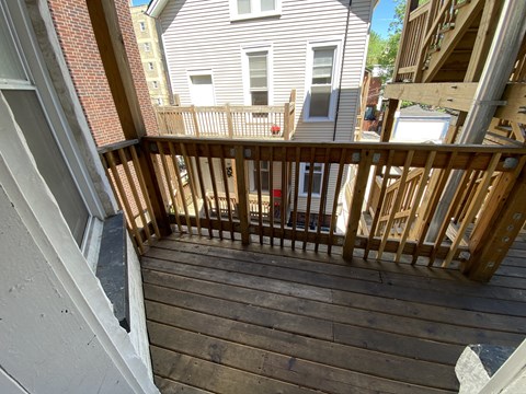 A wooden deck with a railing and a building in the background.