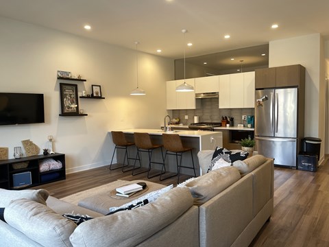 A modern living room with a grey sofa and a kitchen in the background.