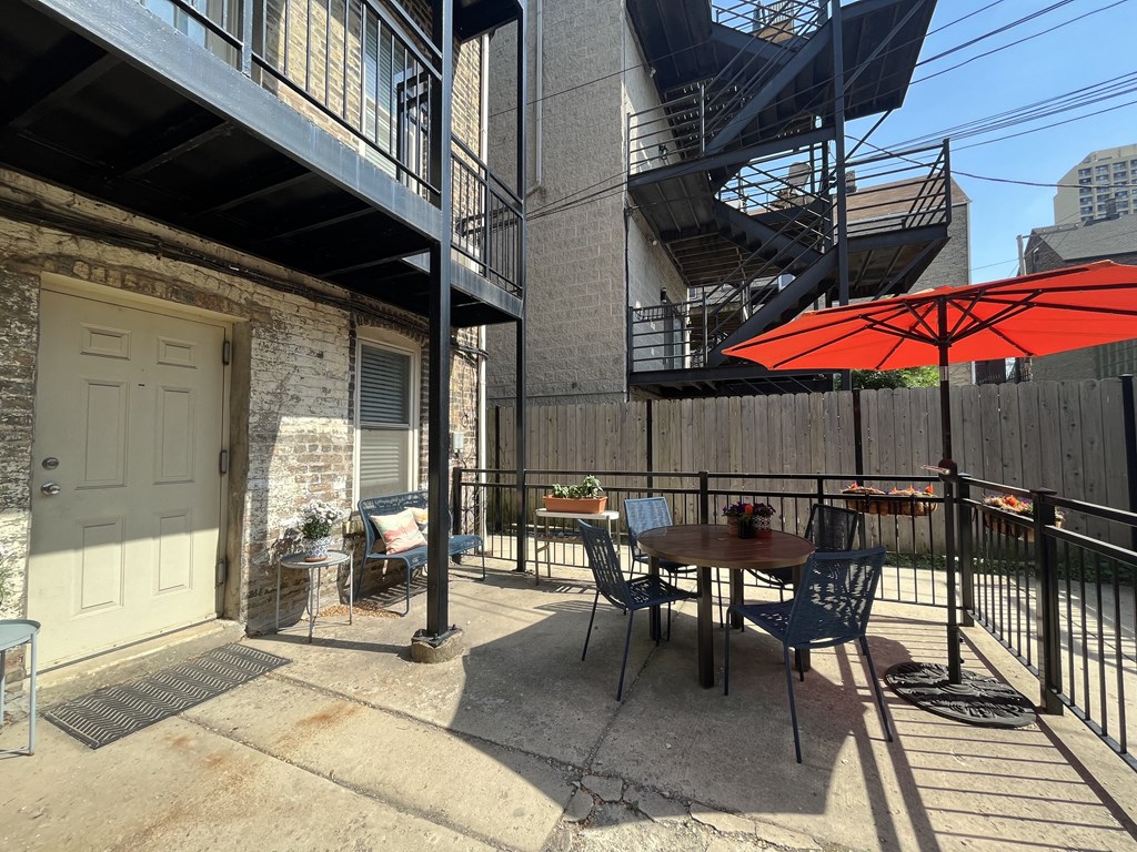 a patio with a table and chairs and a red umbrella
