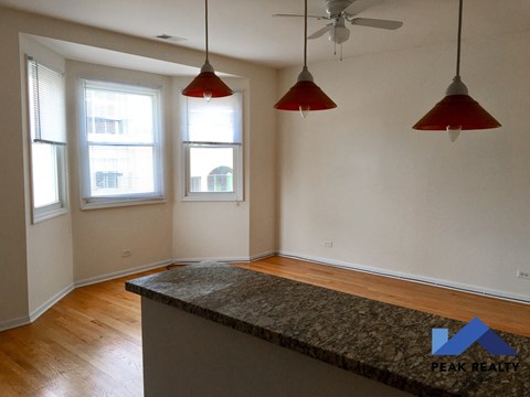 an empty living room with three windows and a kitchen island