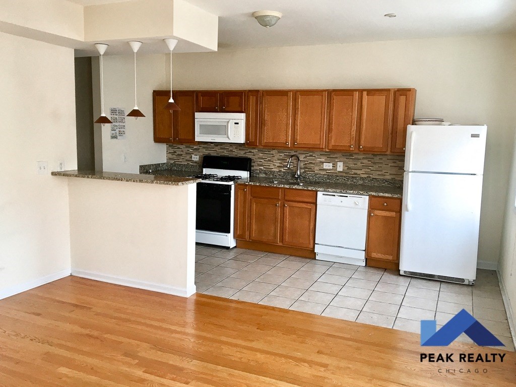 an empty kitchen with white appliances and wooden cabinets