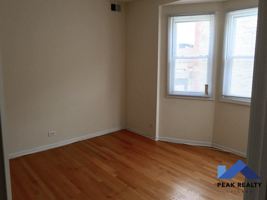an empty room with wooden floors and two windows