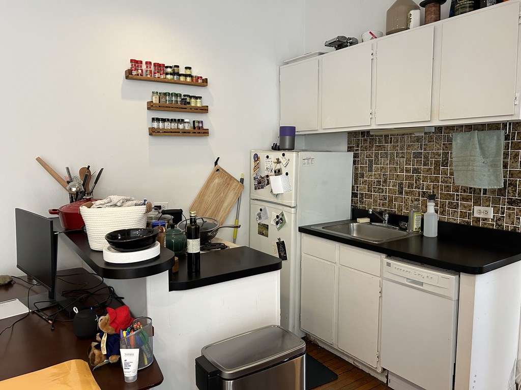 A kitchen with white cabinets and a black countertop.