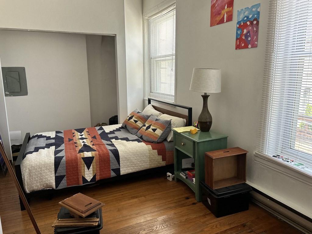 A bedroom with a bed, nightstand, and a painting on the wall.