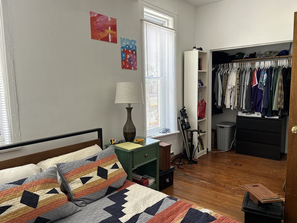A bedroom with a bed, a lamp, a dresser, a wardrobe and a window.