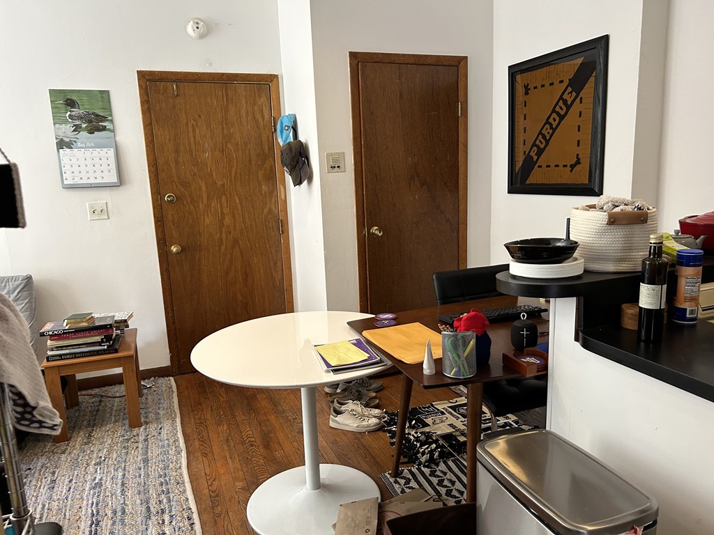 A white table with a yellow book on it is in the middle of a room with two doors.