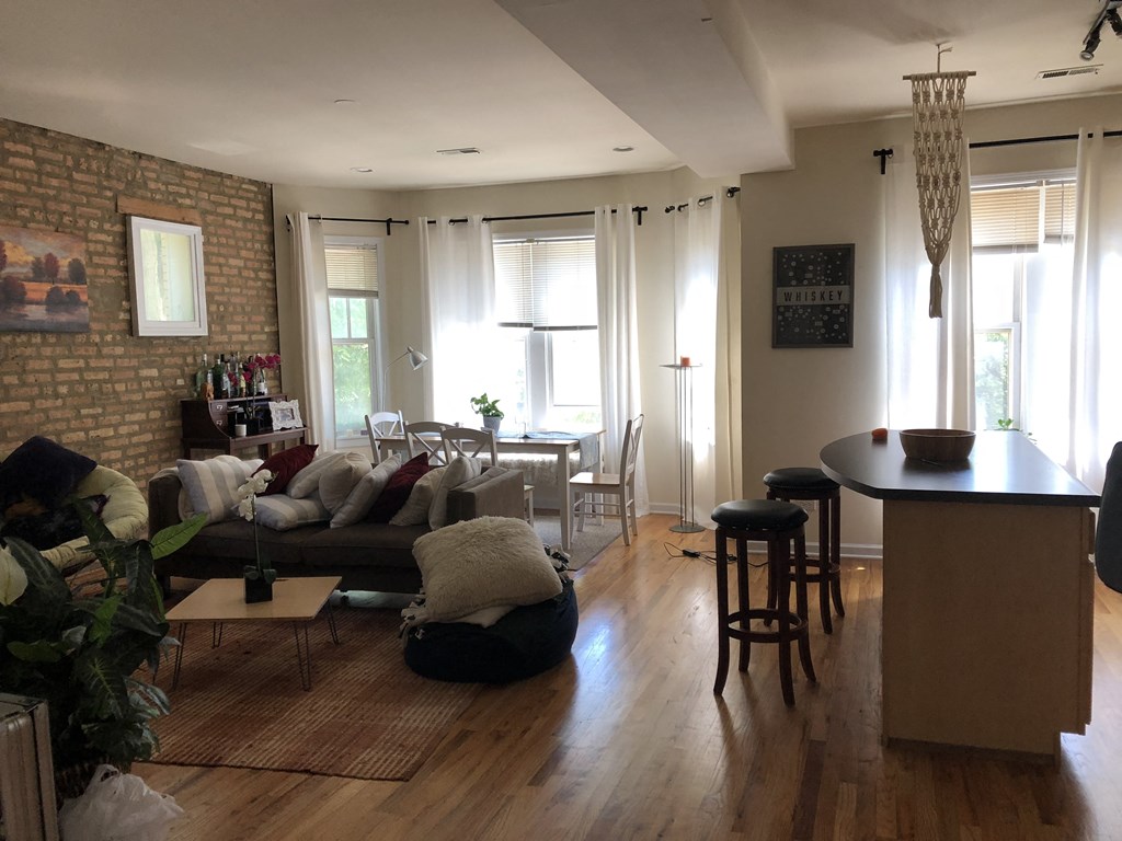 an open living room and dining room with a brick wall and wood floors