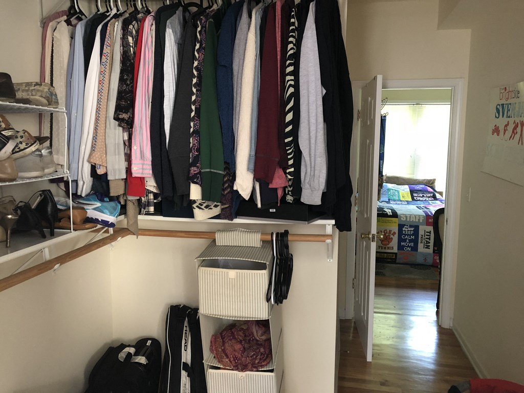 a rack of clothes in a closet in a room with a door