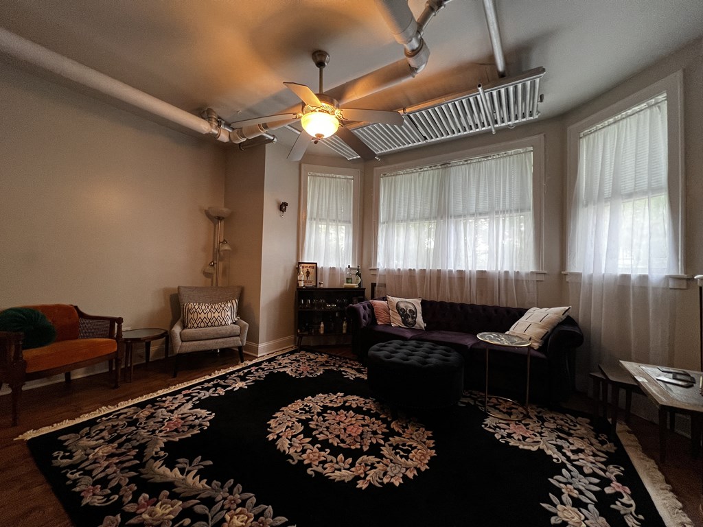 a living room with a large rug and a ceiling fan