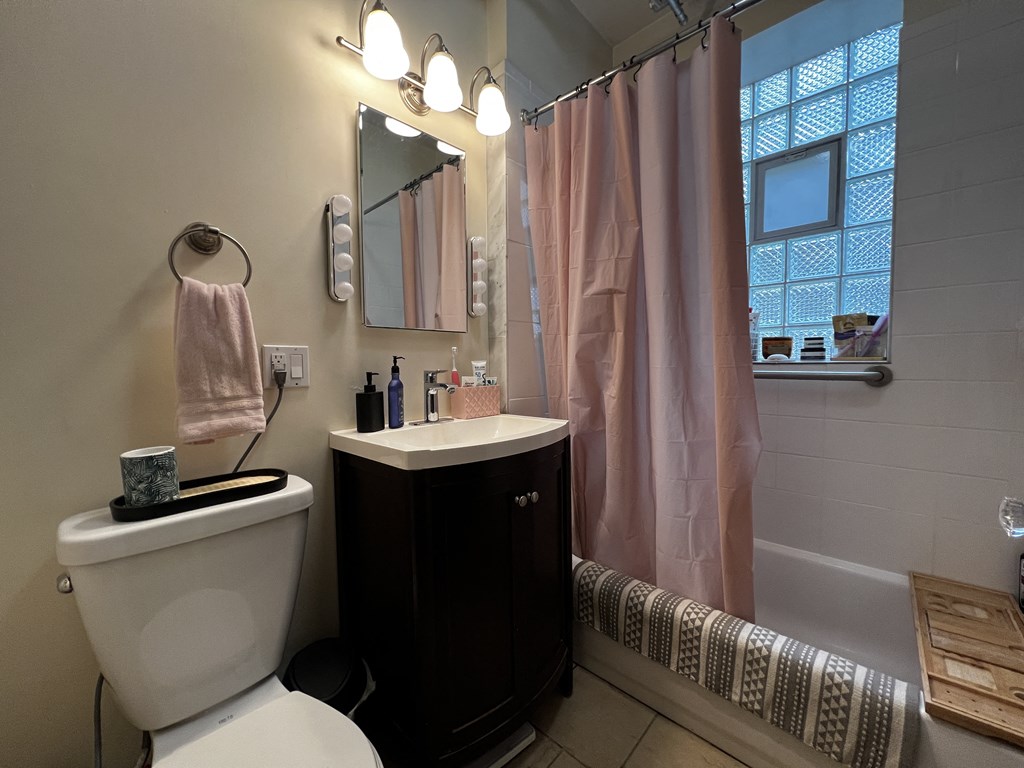 the bathroom has a shower and a toilet and a sink