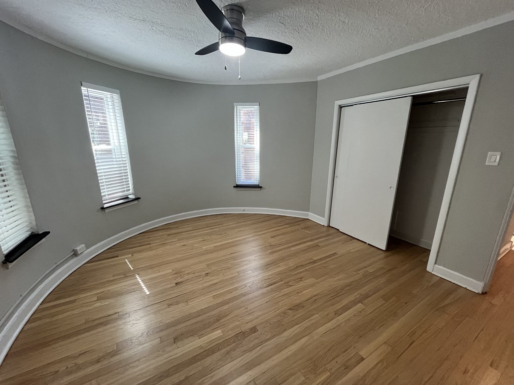 an empty living room with wood floors and a ceiling fan