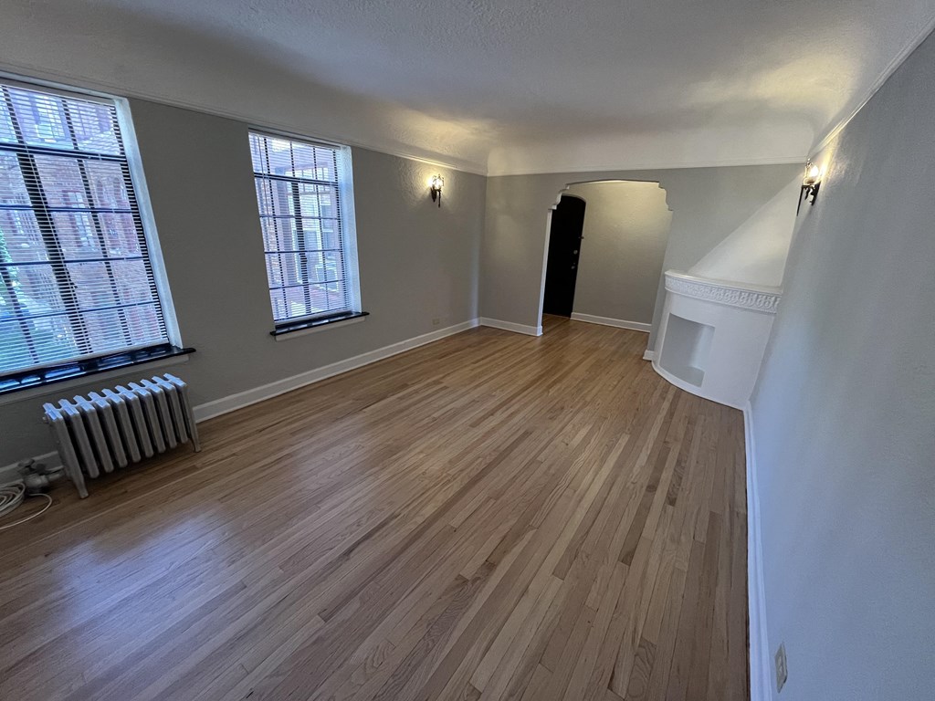 an empty living room with hardwood floors and a radiator