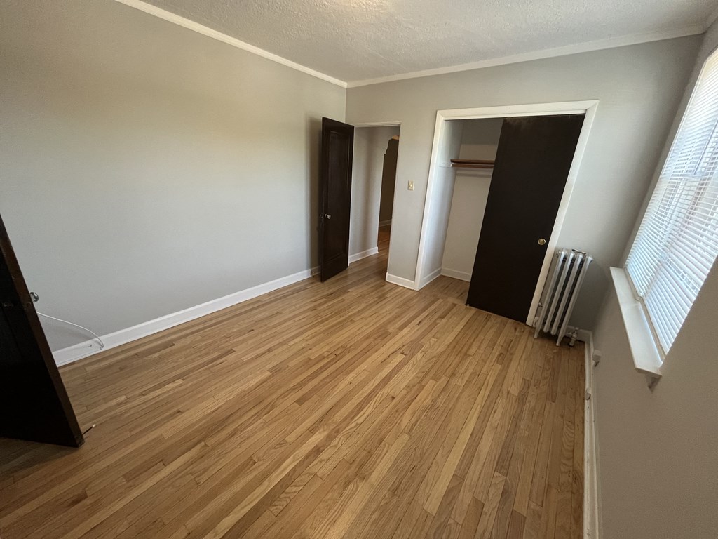 an empty living room with wood flooring and a closet
