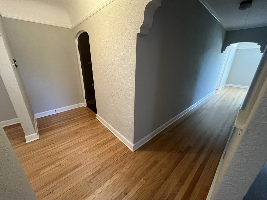 an empty room with wooden floors and grey walls