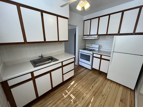 A kitchen with white cabinets and a wooden floor.