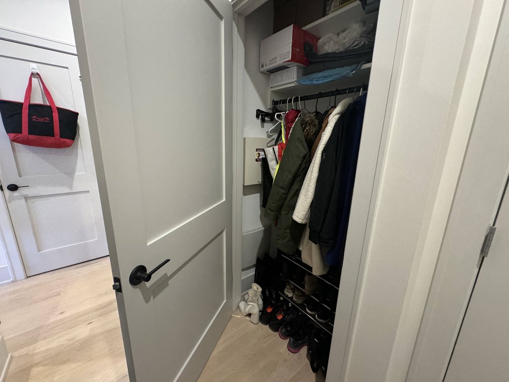 a closet with a white door and a rack of clothes in it