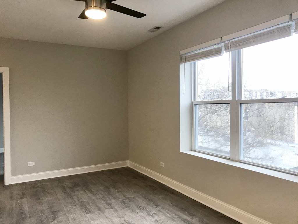 an empty room with a large window and wood floors