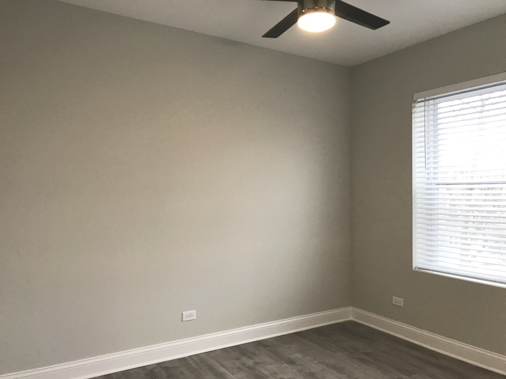an empty bedroom with a ceiling fan and a window