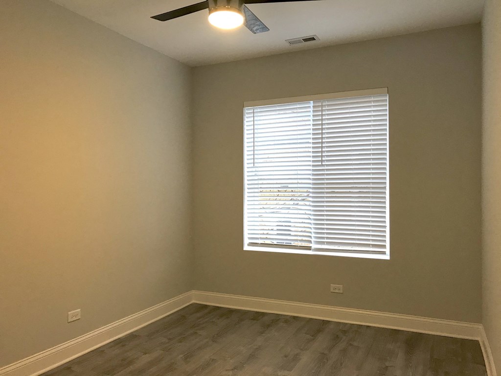 a room with a window and wooden floors and a ceiling fan