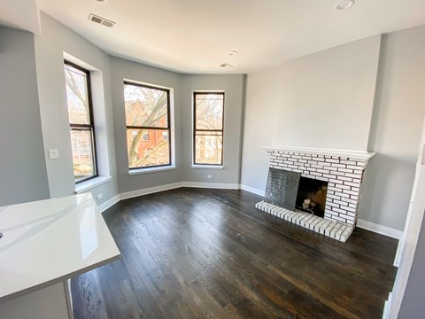 A living room with a fireplace and wood flooring.