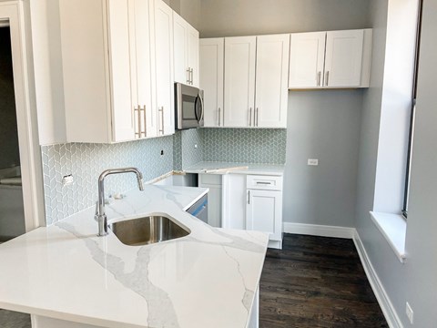 A kitchen with white cabinets and a white counter top.