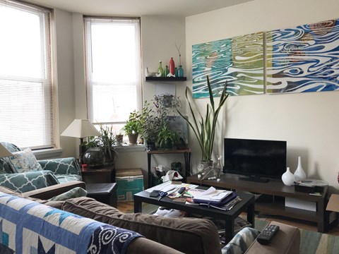 A living room with a couch, a coffee table, a television, and a large painting on the wall.