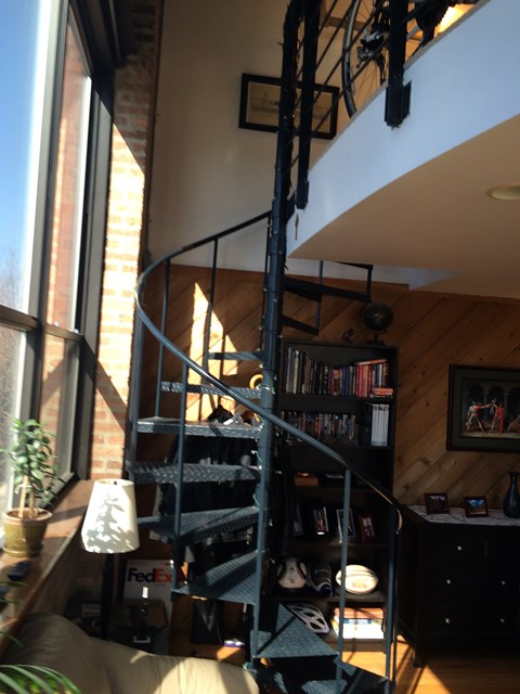A spiral staircase in a home with a black metal railing.