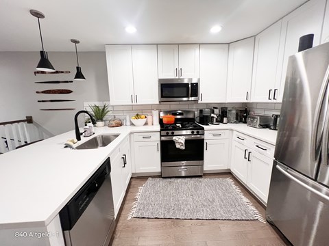 A modern kitchen with white cabinets and stainless steel appliances.